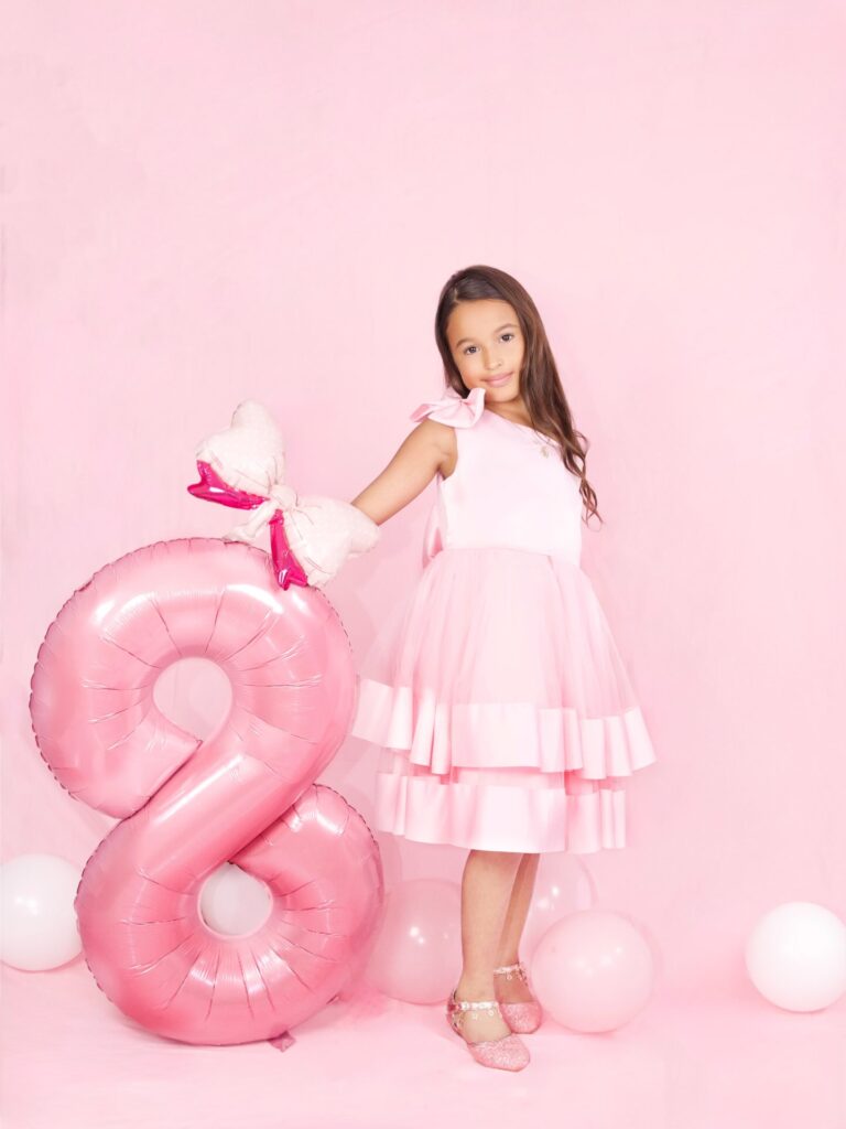 Girl celebrating her eighth birthday in a pink studio set