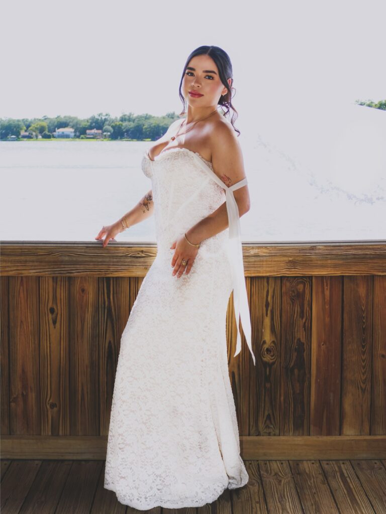 Bride in a lace wedding dress beside a lake